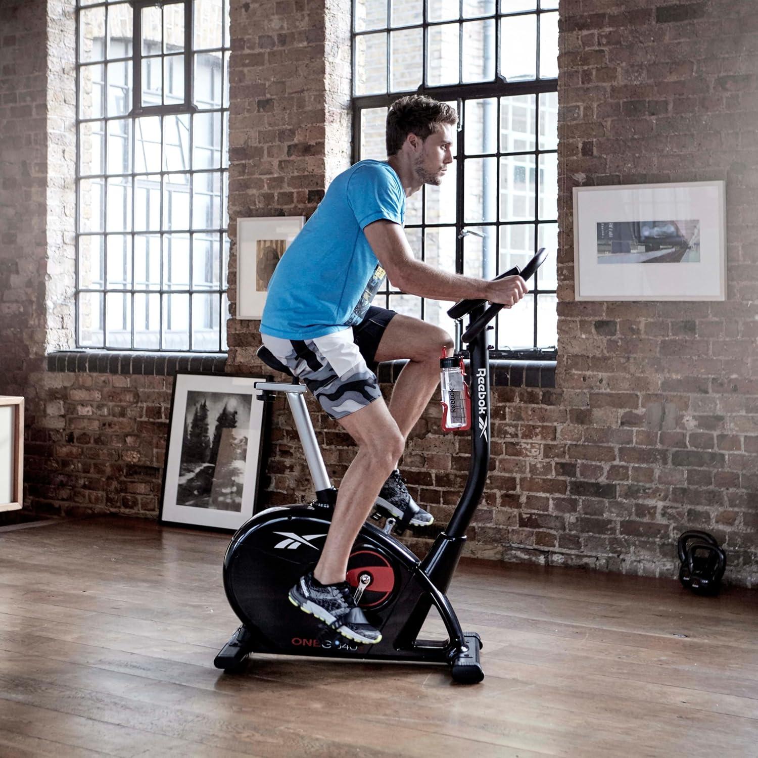 imageReebok Fitness Stationary Bike Bluetooth Compatible Indoor Cycling Bike 24 Resistance Levels 12 Workouts Upright Exercise Bike with Gel Pad SaddleBlack