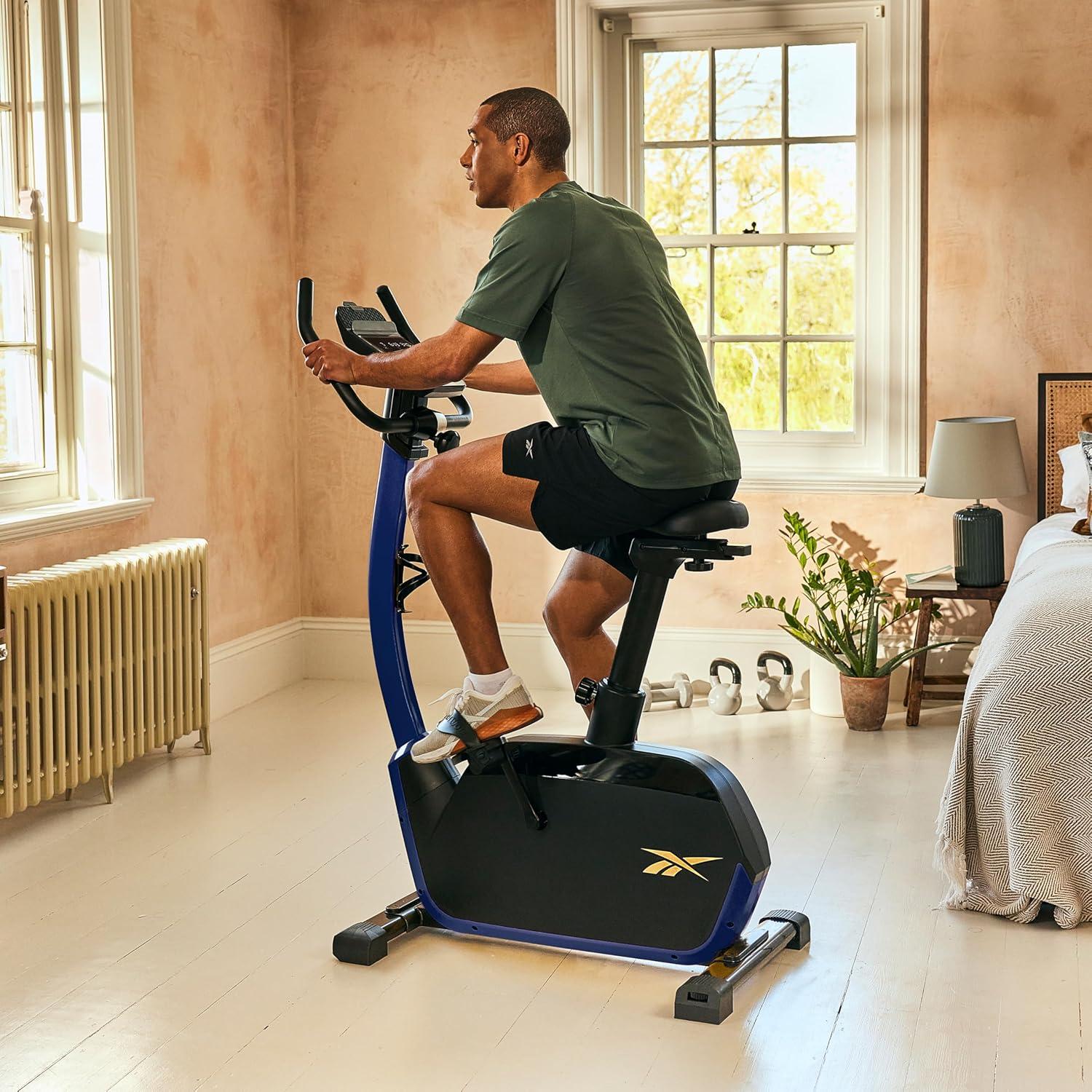 imageReebok Fitness Stationary Bike Bluetooth Compatible Indoor Cycling Bike 24 Resistance Levels 12 Workouts Upright Exercise Bike with Gel Pad SaddleBlue