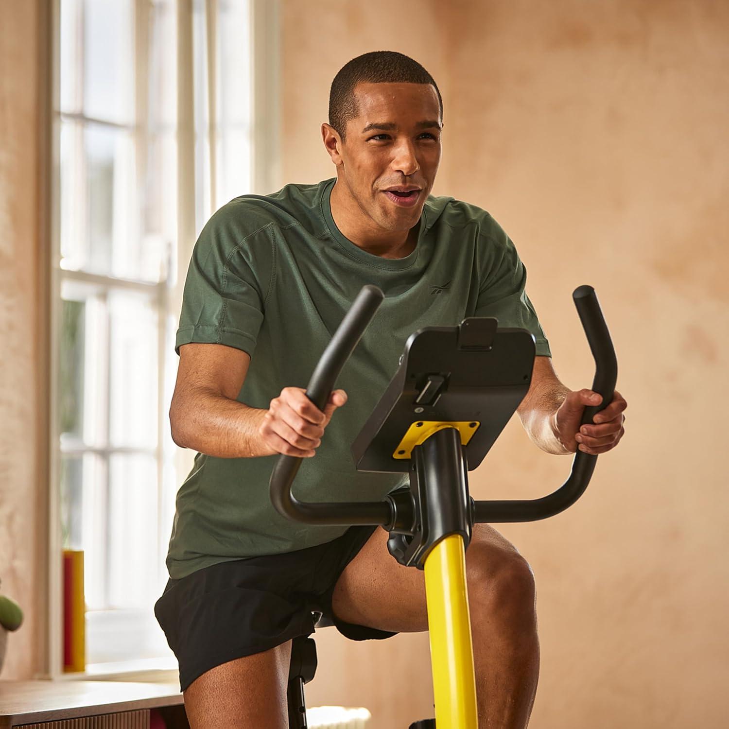 imageReebok Fitness Stationary Bike Bluetooth Compatible Indoor Cycling Bike 24 Resistance Levels 12 Workouts Upright Exercise Bike with Gel Pad SaddleYellow